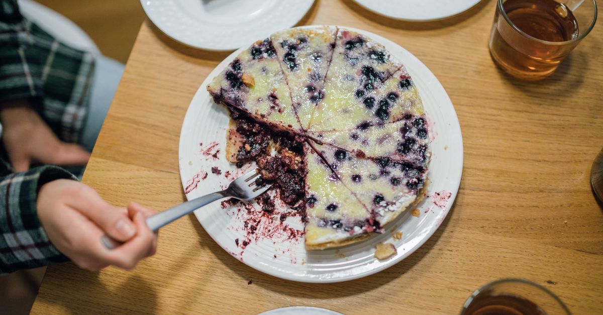 A delicious homemade blueberry pie with a fork held by a hand, perfect for dessert lovers.
